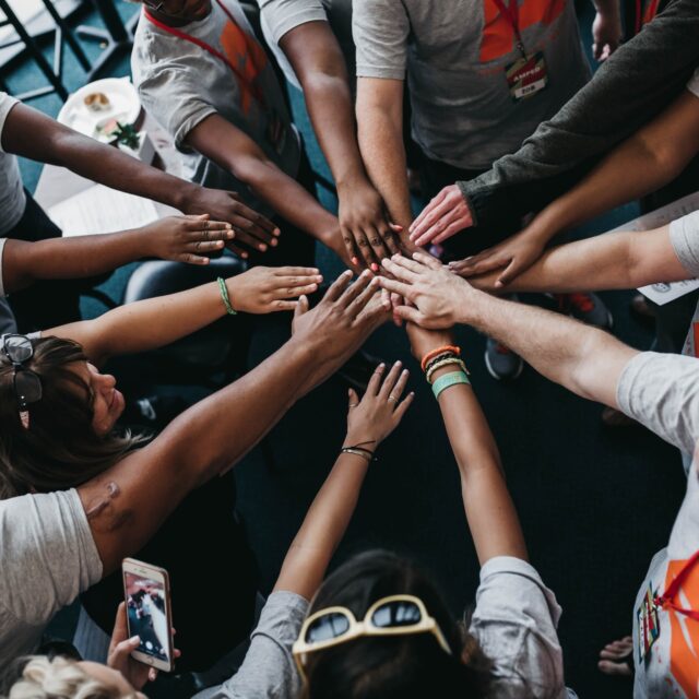 A diverse group joining hands in unity and teamwork.