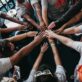A diverse group joining hands in unity and teamwork.