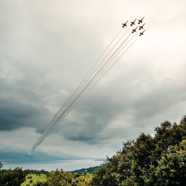 Six aircraft flying in formation with smoke trails against a cloudy sky.