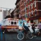 Emergency responders and cyclist on a busy city street near an ambulance.